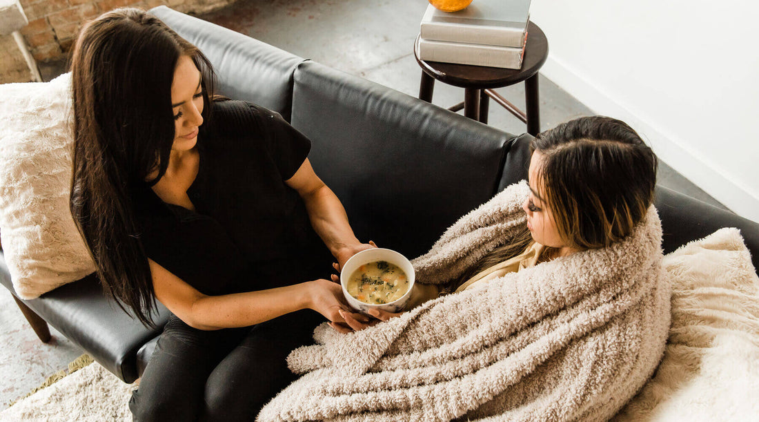Image of girl giving a bowl of soup to a sick friend. 