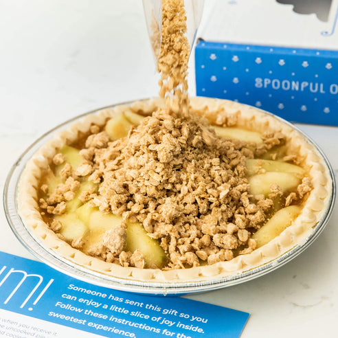 An apple streusel pie with streusel being poured on top