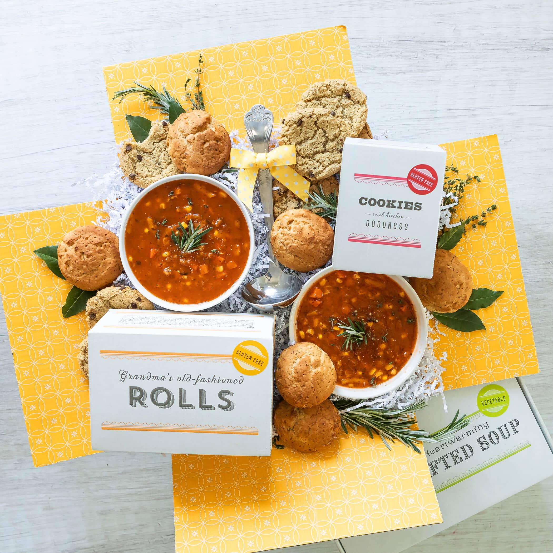 Open garden vegetable soup care package with ladle, cookies, and rolls.