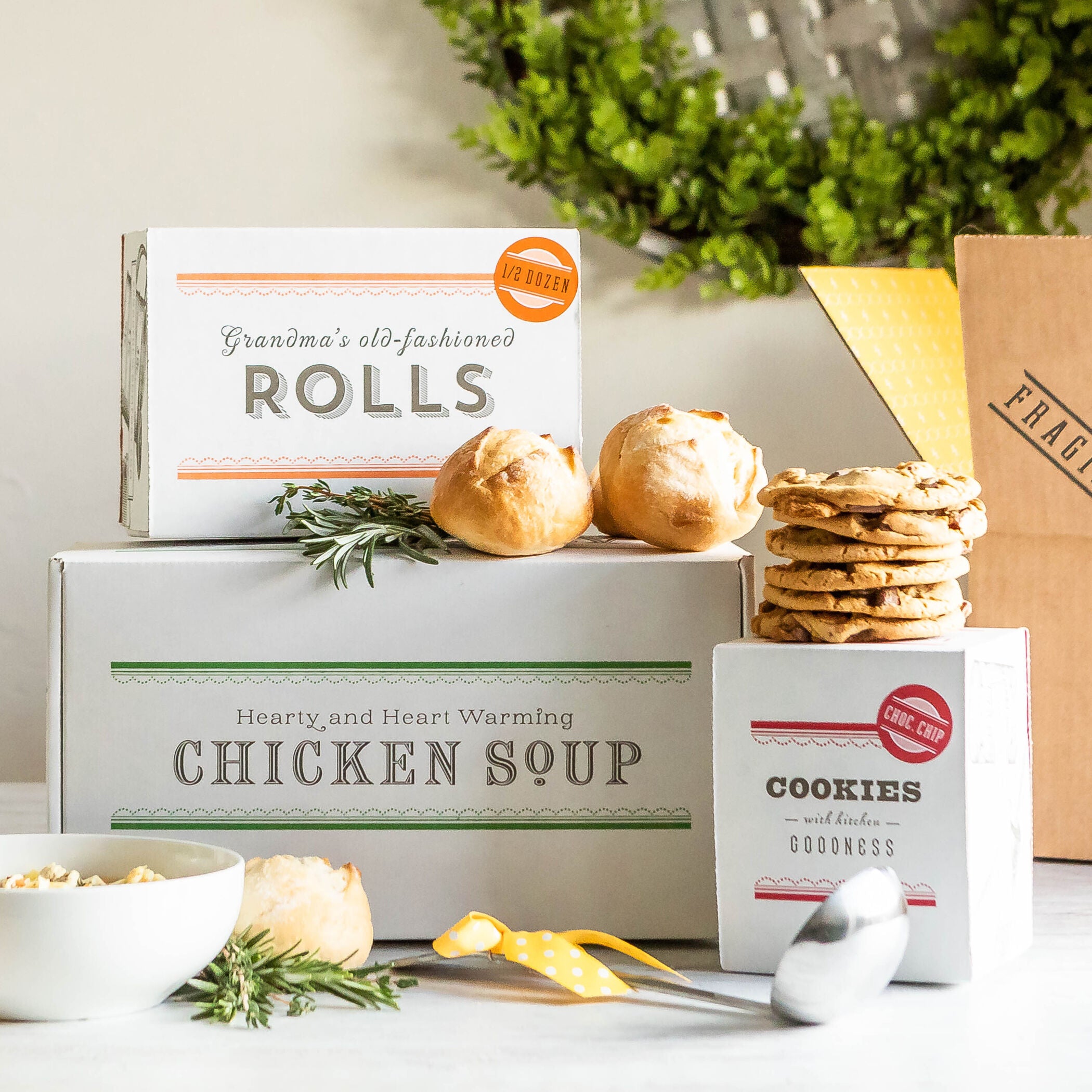 Stacked boxes of Spoonful of Comfort's gluten-free garden vegetable soup, cookies, and rolls.