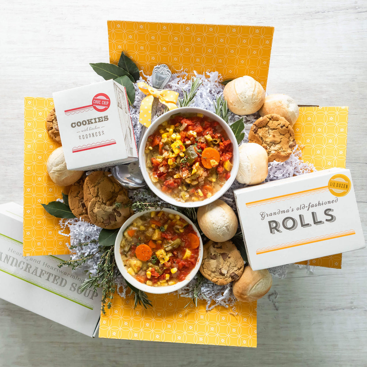Open gluten-free garden vegetable soup care package with ladle, cookies, and rolls.
