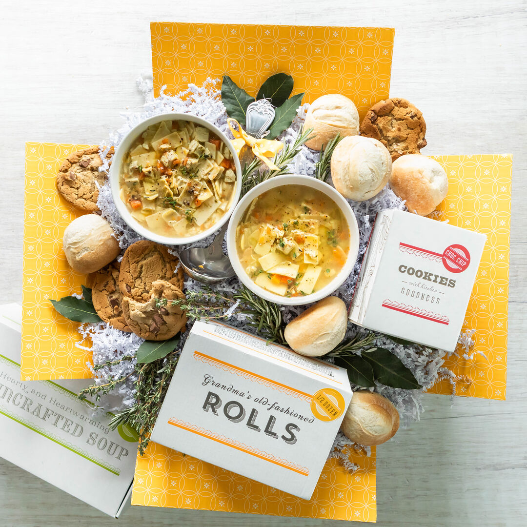 Soup Box with two bowls of soup surrounded by cookies, rolls, ladle and cookies and roll boxes.